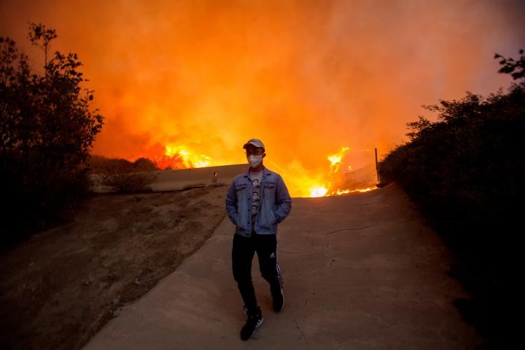 En mand bevæger sig væk fra brandene i Yorba Linda. Omkring 100.000 beboere i det sydlige Californien er beordret evakueret på grund af skovbrande.  Foto: Ringo Chiu/Ritzau Scanpix