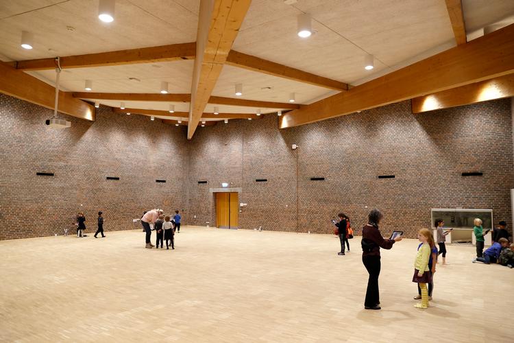Blottet limtræskonstruktion, lyst træ og mørke rødbrune mursten er de gennemgående robuste materialer på skolen som her i multihallen.   Foto: Jens Dresling/POLFOTO