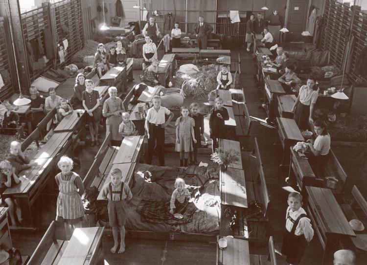 Flygtningeforlægning på Vanløse skole i København 1945, med sovepladser og pulte til undervisning i gymnastiksalen. Foto fra bogen (Frihedsmuseet).  