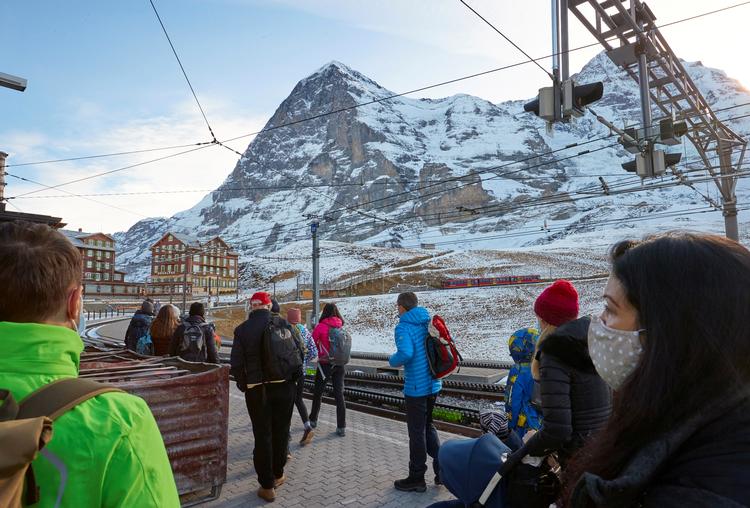 Folk med maske venter på toget til skiresortet  Grindelwald i Schweiz. Italien opfordrer til, at EU lukker alle skisteder henover julen på grund af coronasmitten.  Foto: Denis Balibouse/Ritzau Scanpix