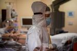 I Italien melder sundhedsmyndighederne igen om svimlende høje antal smittede, døde og indlagte med corona. Tirsdag er i alt 34.577 personer indlagt med virusset på de italienske hospitaler. På billedet ses en sundhedsmedarbejder hjælpe en covid-patient på et sygehus i Rom. Foto: Filippo Monteforte/Ritzau Scanpix