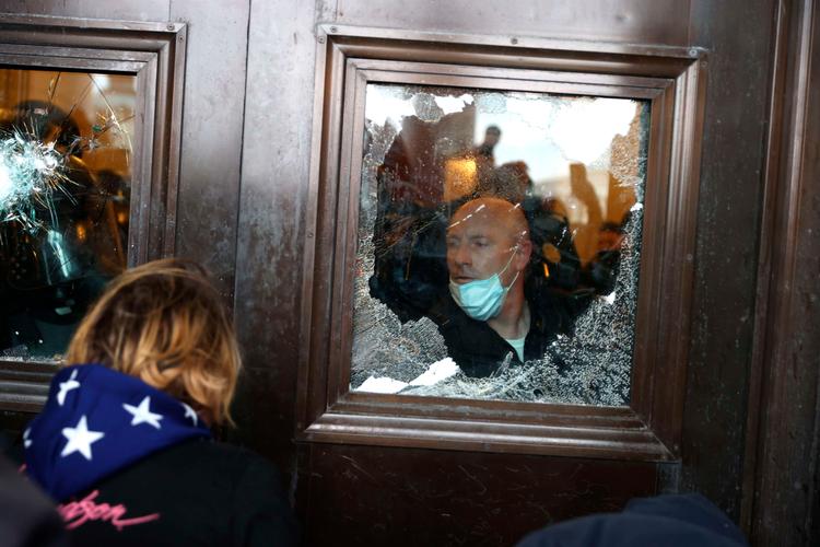     WASHINGTON, DC - JANUARY 06: A Capitol police officer looks oout of a broken window as protesters gather on the U.S. Capitol Building on January 06, 2021 in Washington, DC. Pro-Trump protesters entered the U.S. Capitol building after mass demonstrations in the nation's capital during a joint session Congress to ratify President-elect Joe Biden's 306-232 Electoral College win over President Donald Trump. Tasos Katopodis/Getty Images/AFP == FOR NEWSPAPERS, INTERNET, TELCOS &amp; TELEVISION USE ONLY ==   Foto: Tasos Katopodis/Ritzau Scanpix