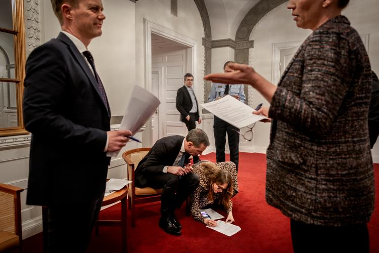 Statsministeriets departmentschef Barbara Bertelsen sidder på gulvet og retter i Justitsministerens, mens statsministeren taler til udenrigsministeren før et pressemøde. Arkivfoto.  Foto: Mads Nissen/POLFOTO