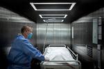 En ældre patient er død af følgevirkningerne af coronavirus på Slagelse Sygehus, og portør Jan Petersen kører den afdøde væk fra stuen.  Foto: Mads Nissen/POLFOTO