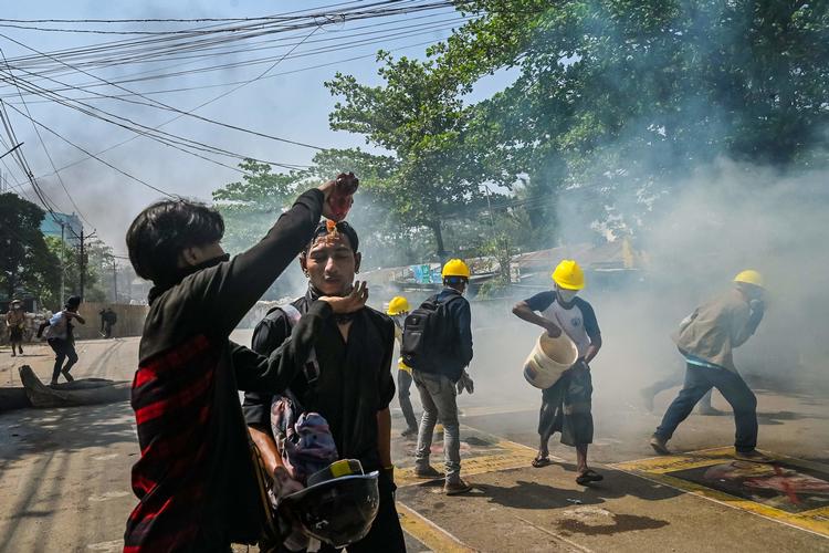 En ung mand hælder vand i øjnene på en meddemonstrant, der har fået for meget tåregas, under en demonstration i Myanmars hovedby, Yangon, tidligere i denne måned.  Foto Str