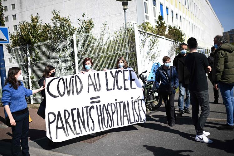 Forældre udenfor et gymnasium i Drancy udenfor Paris med knap 2.000 elever krævede ved en demonstration mandag gymnasiet lukket.. 'Covid på gymnasiet - forældre på hospitalet', står der på banneret. På et år har 20 forældre til elever på skolen mistet livet som ofre for epidemien. Foto: Christophe Archambault/Ritzau Scanpix