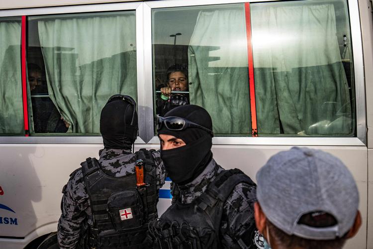  34 børn i alderen fra 3 til 14 år er blevet overdraget til en russisk delegation i Syrien. Og flere er på vej. På billedet er en bus ved at fragte nogle af børnene fra byen Qamishli, mens kurdiske styrker ser til. Foto: Delil Souleiman/Ritzau Scanpix