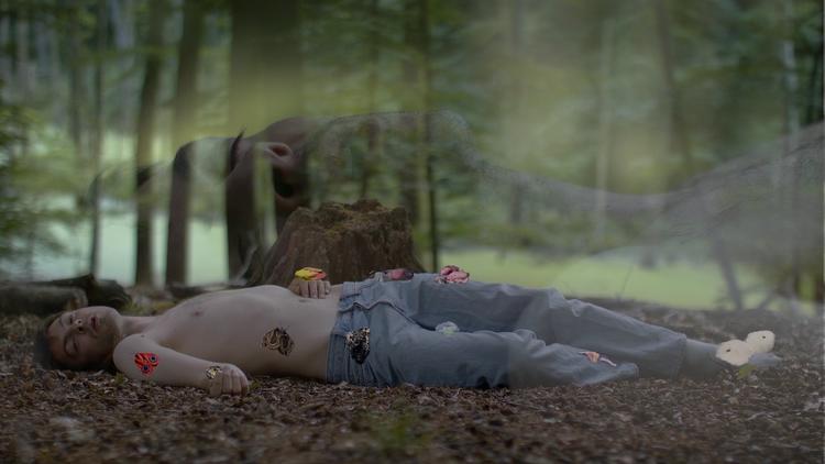 Kim Richard Adler Mejdahls naturfællesskaber er magiske på en måde, hvor der i den grad er plads til monstre. Og morsende møl!  Foto: Stillbillede fra videoprojektion med kunstneren syngende i skovbunden