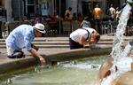 Mange danskere længes efter sydens sol og varme som her på Plaza de la Virgen i den spanske by Valencia, hvor turisterne under en hedebølge i 2018 måtte køle sig i fontænen. Foto: Heino Kalis/Ritzau Scanpix