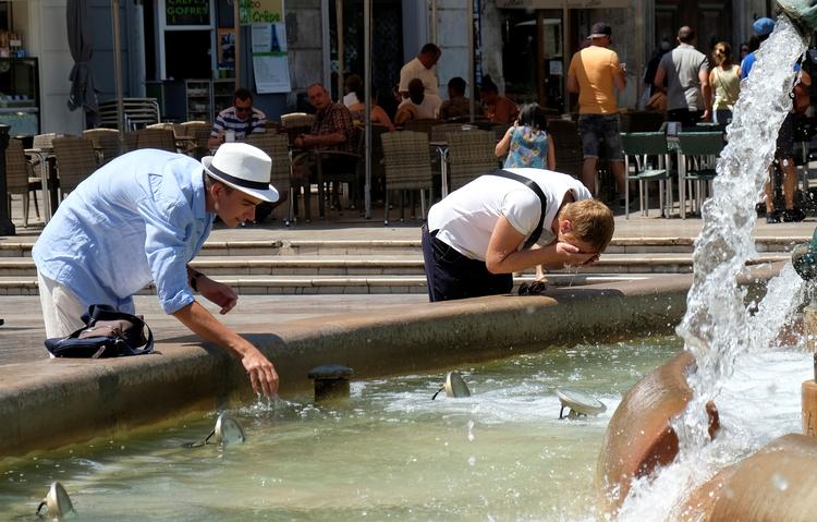 Mange danskere længes efter sydens sol og varme som her på Plaza de la Virgen i den spanske by Valencia, hvor turisterne under en hedebølge i 2018 måtte køle sig i fontænen. Foto: Heino Kalis/Ritzau Scanpix