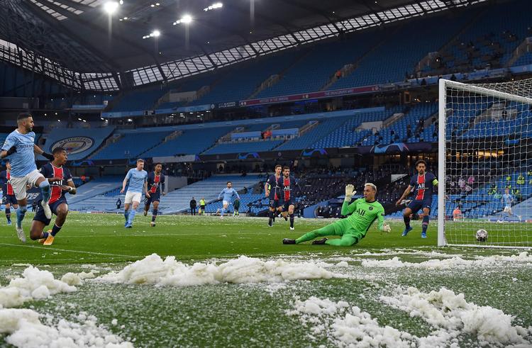 Resterne af nogle voldsomme haglbyger lå stadig på Etihad Stadiums græstæppe, da Manchester Citys Riyad Mahrez (tv.)  bragte sit hold foran i starten af Champions League-opgøret tirsdag aften.  Foto: Paul Ellis/Ritzau Scanpix