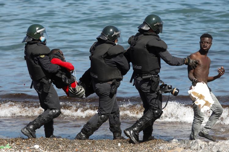  Spanske tropper bærer og eskorterer marokkanske migranter væk fra El Tarajal beach nær den spansk-marokkanske grænse. Spaniens premierminister, Pedro Sánchez, har lovet at genoprette roen i den spanske enklave Ceuta i Marokko. Foto: Jon Nazca/Ritzau Scanpix