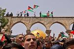 Våbnene er lagt for en stund, men der blev alligevel smidt tåregas i den hellig by, hvor palæstinensere her ses med deres flag under sammenstød med de israelske styrker foran al-Aqsa-moskeen.  Foto: Ahmad Gharabli/Ritzau Scanpix