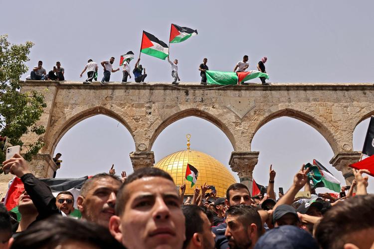 Våbnene er lagt for en stund, men der blev alligevel smidt tåregas i den hellig by, hvor palæstinensere her ses med deres flag under sammenstød med de israelske styrker foran al-Aqsa-moskeen.  Foto: Ahmad Gharabli/Ritzau Scanpix