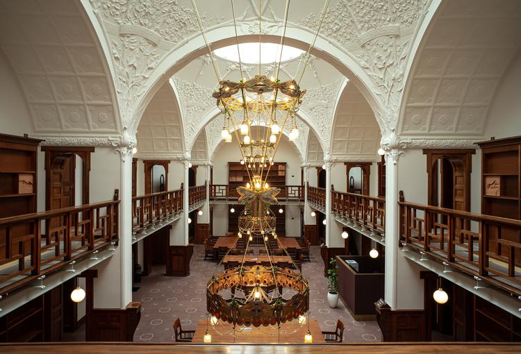 Lofter, lysekroner og møbler i læsesalen er blevet restaureret nænsomt. Bøgerne er væk, men reolerne består – nu med værker af kunstnerduoen benandsebastian.  Foto: Helene Høyer Mikkelsen