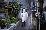 En mand iført sikkerhedsdragt sprøjter desinficerende væske ud på alle flader ved et hus i Bangkok, hvor en hel familie er blevet smittet med corona. Foto Claus Blok Thomsen