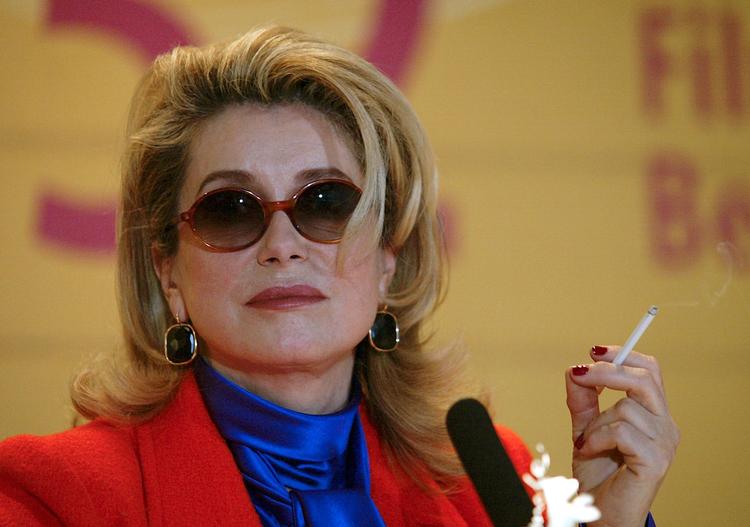 Mange har skrottet cigaretter de seneste år, men i fransk film pulses der stadig løs. Her ses den franske filmstjerne  Catherine Deneuve med en cigaret i hånden - dog ikke i en film, men under et pressemøde ved Berlinalen. Foto: Tom Maelsa/Ritzau Scanpix
