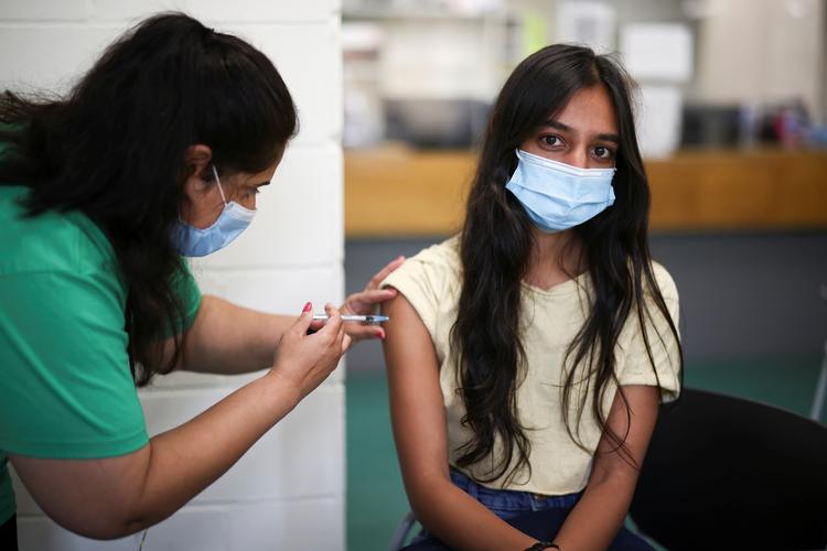 En britisk kvinde modtager et skud Pfizer-vaccine søndag. Unge briter opfordres nu ikke blot til at lade sig vaccinere; landets datingtjenester tilbyder også at booste deres online-profiler. Vaccination skal gøres sexet. Foto: Henry Nicholls/Ritzau Scanpix