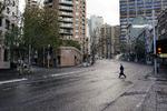 En fodgænger krydser en stille gade i Sydney. 18 millioner australiere, svarende til 70 procent af befolkningen, er nu underlagt en eller anden form for coronarestriktioner. Foto: Loren Elliott/Ritzau Scanpix