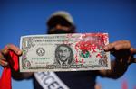 En mand holder en blodig dollar-seddel med billedet af den brasilianske præsident, Jair Bolsonaro. Manden deltog i demonstrationen i Brasilia mod Bolsonaros håndtering af coronakrisen.  Foto: Sergio Lima/Ritzau Scanpix