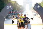 Jonas Vingegaard (t.v.) med datteren Frida på armen nyder karrierens største øjeblik på Champs-Élysées. sammen med konkurrenterne Tadej Pogacar og Richard Carapaz.
 Foto: Garnier Etienne/Ritzau Scanpix