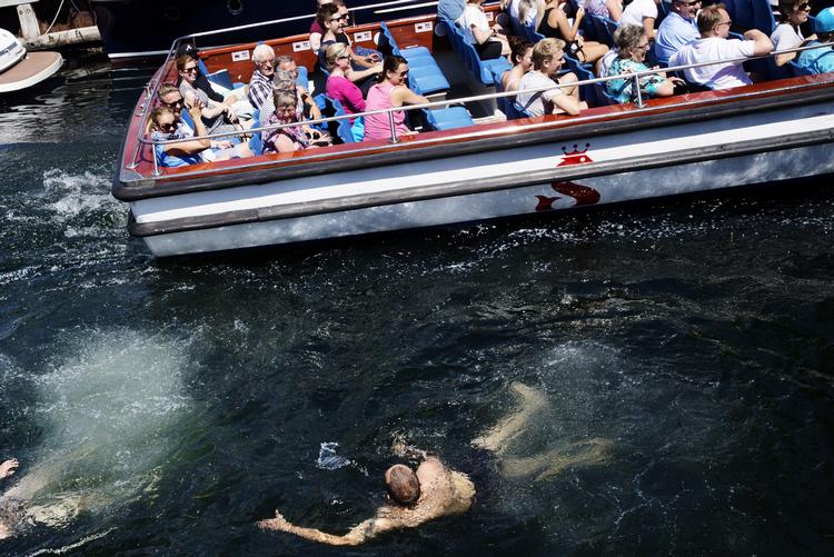 Det er ikke noget nyt, at folk bader ulovligt i Københavns Havn. Billedet her er fra 2014, hvor en båd fra kanalrundfarten får selskab af et par københavnere, der svømmer uden for badezonerne.  Foto: Miriam Dalsgaard/POLFOTO