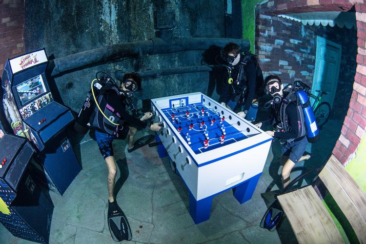 Hvem der vinder matchen, melder historien ikke noget om., men bordfodboldkampen foregår i det 60 meter dybe Deep Dive Dubai-bassin.  Foto: Deep Dive Dubai