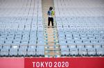 Tilskuerpladserne er tomme under OL i Tokyo for at begrænse risikoen for coronasmitte, men frivillige går alligevel rundt med skilte, der minder om at spritte hænder af og holde afstand.
 Foto: Molly Darlington/Ritzau Scanpix