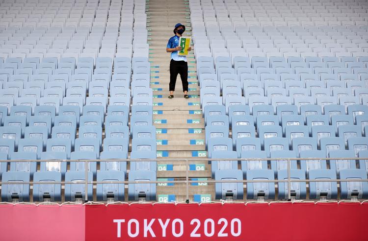 Tilskuerpladserne er tomme under OL i Tokyo for at begrænse risikoen for coronasmitte, men frivillige går alligevel rundt med skilte, der minder om at spritte hænder af og holde afstand.
 Foto: Molly Darlington/Ritzau Scanpix