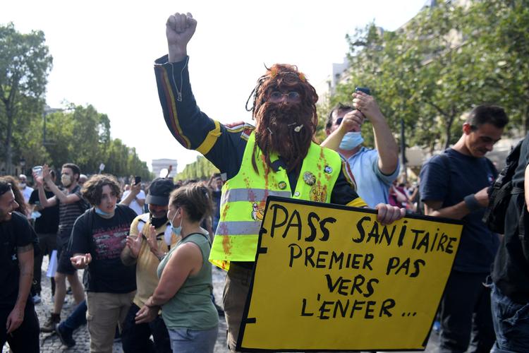    'Sundhedspas, første skridt mod helvede', står der på demonstrantens skilt. Flere steder i Frankrig demonstrerede modstandere af det kommende coronapas i weekenden, og regeringen frygter nye aktioner. Foto: Alain Jocard/Ritzau Scanpix