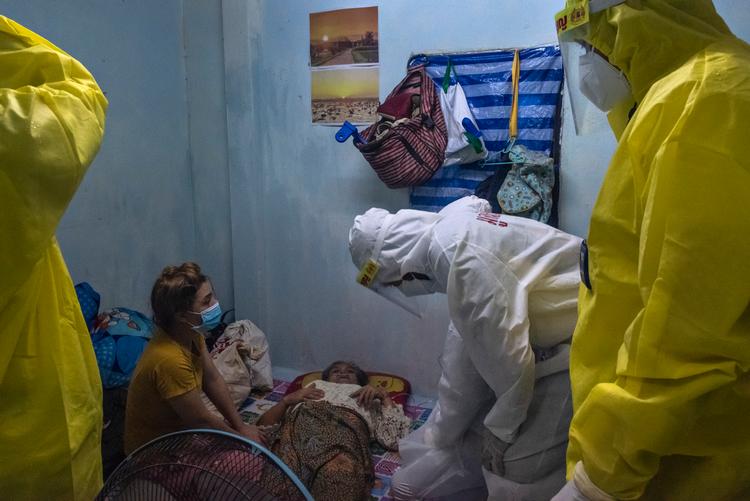 Frivillige bringer ilt ind til en ældre kvinde i slumkvarteret Khlong Toei i Bangkok. Den thailandske regering indrømmede i denne uge, at nogle coronapatienter »desværre« nok kommer til at dø hjemme i den kommende tid, fordi hospitalerne er overfyldte. Foto: Claus Blok Thomsen