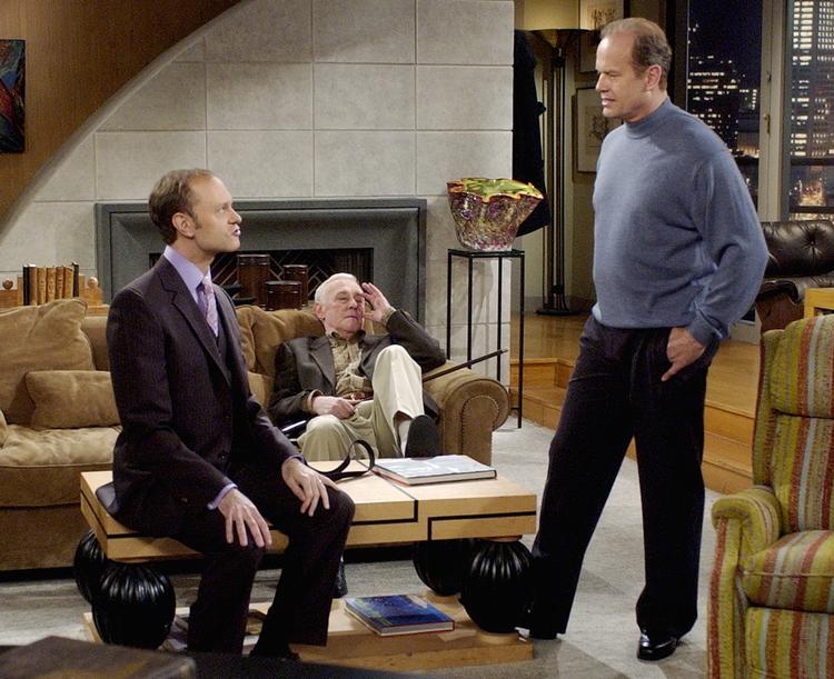 Frasier Crane får sig en snak med sin bror, Niles, der har sat sig på sofabordet, mens deres far Martin Crane tager en slapper i sofaen.  Foto: AP Photo/ Reed Saxon /Ritzau Scanpix