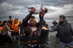    En frivillig bærer et barn i land på Lesbos, Grækenland, i 2015. Seks år senere udspiller de samme scener sig flere steder i Europa. Fra Litauen i nord til Sicilien i syd kom tusindvis af flygtninge og migranter alene i juli i år. Foto Ap Photo/santi Palacios