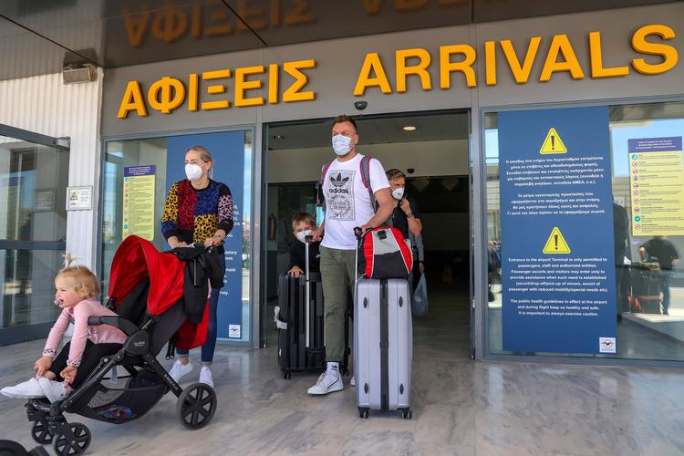 Turister ruller kufferter og børn ud af Heraklion-lufthavnen i Grækenland, hvor turistsæsonen har været godt i gang siden midten af maj. Foto: Stefanos Rapanis/Ritzau Scanpix