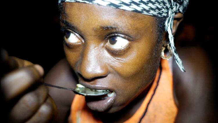 Lafty spiser sit første måltid i lang tid midt om natten på et madmarked i Liberia. Foto: Neflix 