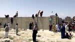 Afghanere klatrer over en pigtråds beskyttet mur til lufthavnen i Kabul. Foto: Reuters Tv/Ritzau Scanpix