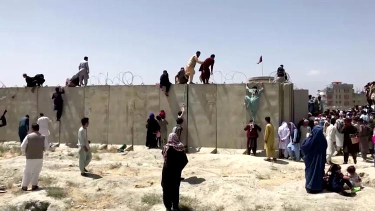Afghanere klatrer over en pigtråds beskyttet mur til lufthavnen i Kabul. Foto: Reuters Tv/Ritzau Scanpix