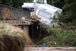 En campingvogn hænger på kanten af en bro over Erft-floden ved Euskirchen, der blev ramt af katastrofale oversvømmelser i juli måned.  Foto: Marius Becker/Ritzau Scanpix