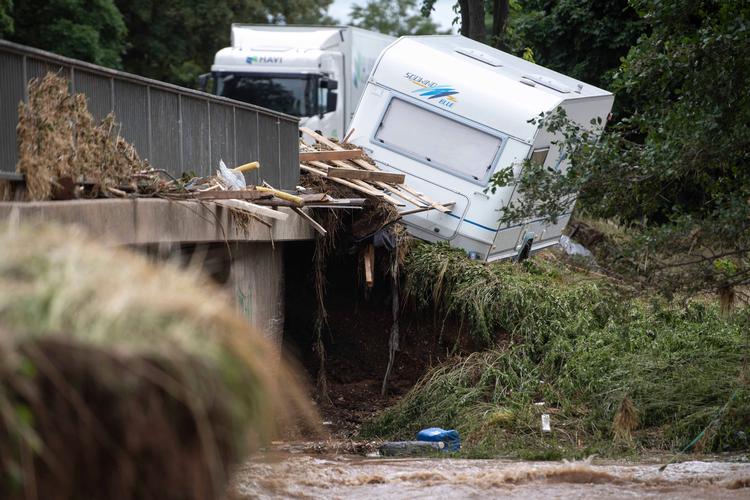 En campingvogn hænger på kanten af en bro over Erft-floden ved Euskirchen, der blev ramt af katastrofale oversvømmelser i juli måned.  Foto: Marius Becker/Ritzau Scanpix