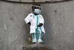 Den ikoniske Manneken Pis-statue i Bruxelelles er kittelklædt som hyldest til sundhedspersonalets indsats under coronapandemien.  Foto: Francois Lenoir/Ritzau Scanpix