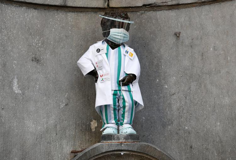 Den ikoniske Manneken Pis-statue i Bruxelelles er kittelklædt som hyldest til sundhedspersonalets indsats under coronapandemien.  Foto: Francois Lenoir/Ritzau Scanpix