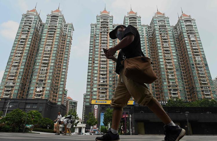 En mand passerer et stort ejendomskompleks i Guangzhou, som er ejet af ejendomsselskabet Evergrande.  Foto: Noel Celis/Ritzau Scanpix