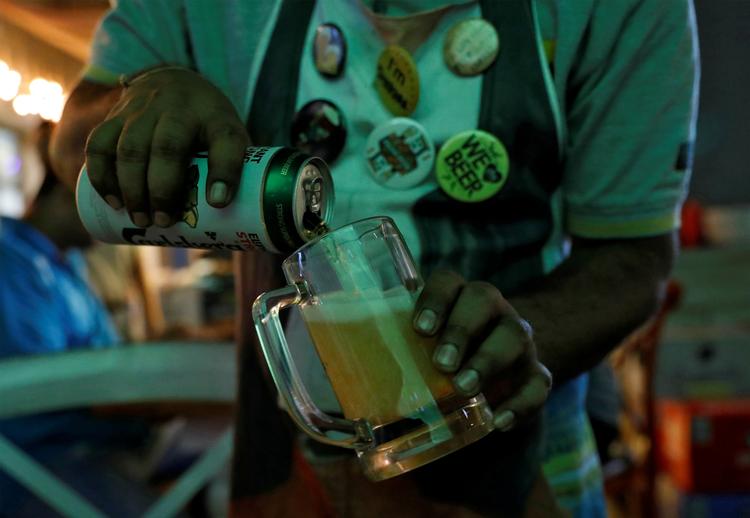 En bartender i den indiske by Mumbai hælder en øl fra Carlsberg op. Foto: Danish Siddiqui/Ritzau Scanpix