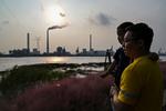 En far og hans datter ved bredden af Huangpu-floden i Shanghaii, hvor de ser over på et kraftværk. Stigende kulpriser har ført til, at mange kraftværker har skåret ned på deres produktion af elektricitet.    Foto: Hector Retamal/Ritzau Scanpix