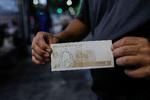 Grundet inflation i den lokale valuta har mange i Venezuela brugt den mere stabile amerikanske dollar som valuta. I Caracas viser en mand en nytrykt bolivar.  Foto: Manaure Quintero/Ritzau Scanpix