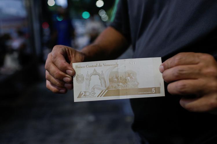 Grundet inflation i den lokale valuta har mange i Venezuela brugt den mere stabile amerikanske dollar som valuta. I Caracas viser en mand en nytrykt bolivar.  Foto: Manaure Quintero/Ritzau Scanpix