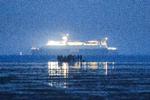 På dette foto fra 22. september sidste år ses en gruppe migranter på stranden ved Gravelines i det nordlige Frankrig, mens en dansk DFDS-færge sejler i Den Engelske Kanal i baggrunden.  Foto: Sameer Al-doumy/Ritzau Scanpix