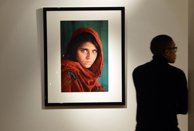 Fotografen Steve McCurry tog billedet af den afghanske pige Sharbat Gula i flygtningelejren Nasir Bagh nær Peshawar i Pakistan i 1984.  På det tidspunkt fik han ikke pigens navn og gav billedet titlen 'Afghan Girl'. I 1985 blev det verdensberømt, da det landede på coveret af National Geographic. Her ses det på en auktion hos Christie's i 2012. 

 Foto: Stan Honda/Ritzau Scanpix