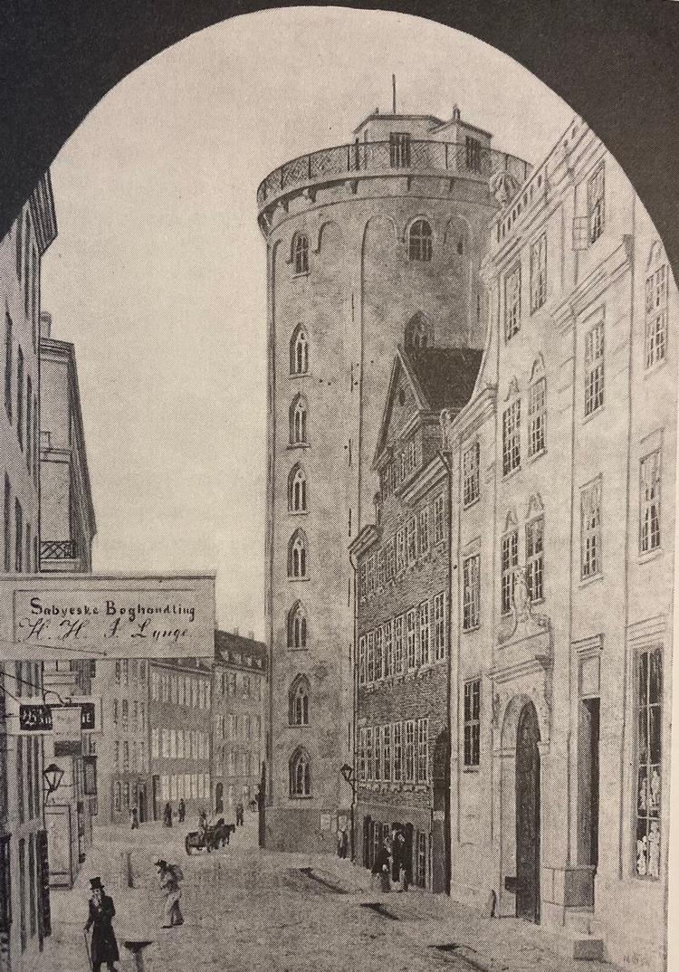 Fra omkring 1800 samledes de fleste af Københavns boglader, forlag, bladredaktioner og trykkerier i området omkring Købmagergade. Bygningen op til Rundetårn husede fra 1820 den nye studenterforening. Maleri af Carsten Henrichsen 1840.   