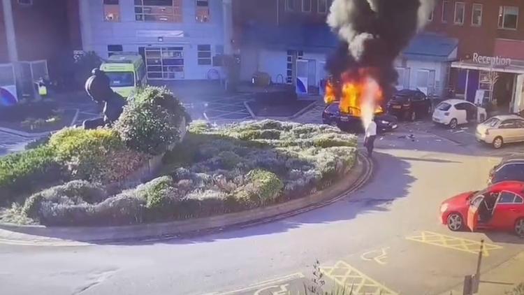 Overvågningsbilleder viser en mand, der forsøger at slukke ilden i den taxa, der eksploderede foran Liverpool Women's Hospital søndag. Foto: Cctv/Ritzau Scanpix